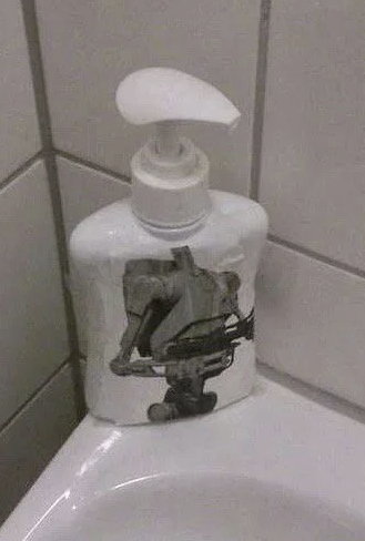 soap dispenser with a robot from the prequel Star Wars movies on it but using the top part of the dispenser as a head.