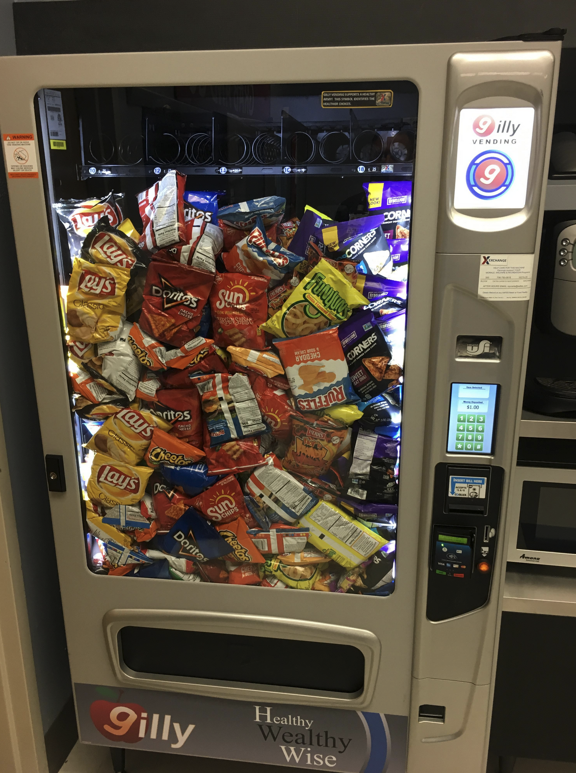 Vending machine with all small bags of chips released and have stacked up pressed against the front glass up to almost the top of the inside of the machine.