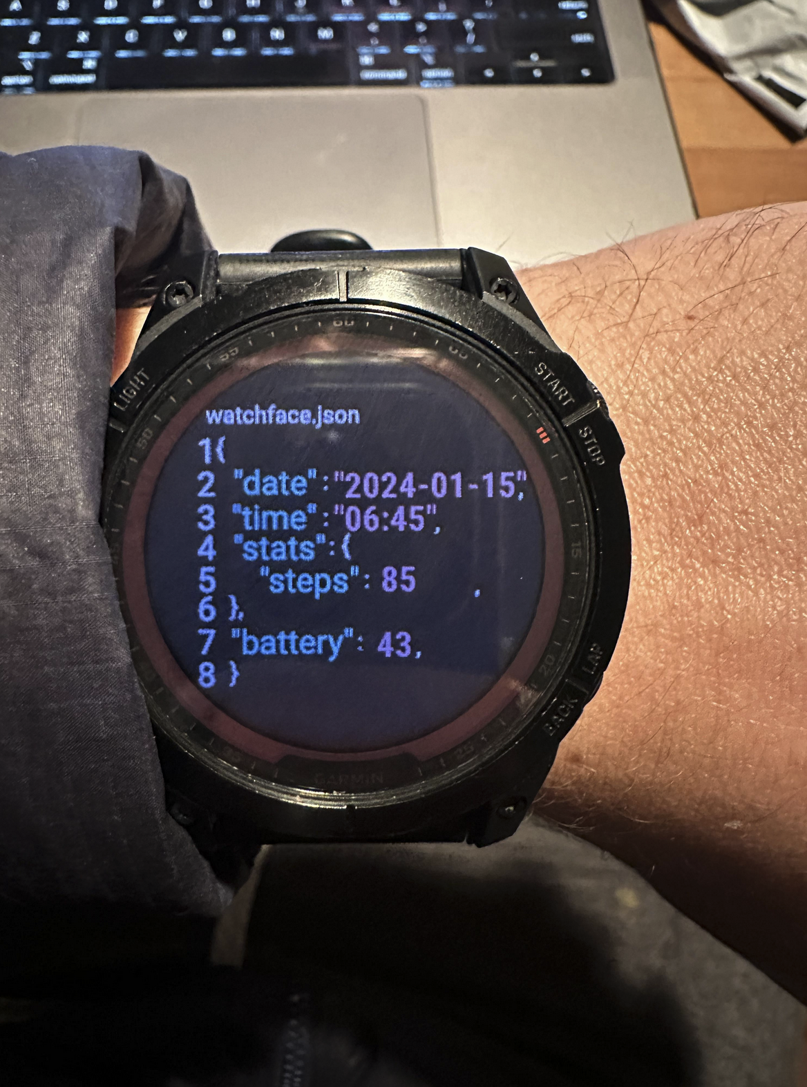 Digital Garmen watch with "watchface.json" with items like "date" and "time" and "steps" and "Battery life" all in JSON defined on the watch screen in code.