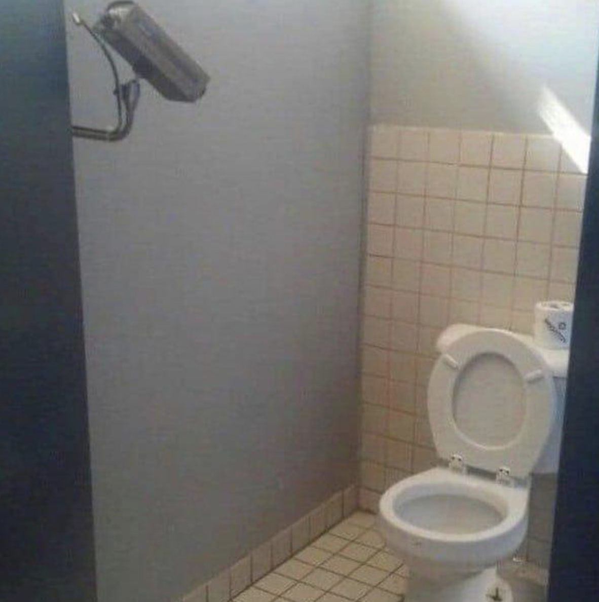 bathroom stall where an obvious video camera is pointing straight to an open inviting toilet.