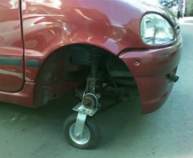 closeup of a passenger side area where a tire would be. The tire has been replaced by a wheel from a shopping cart.