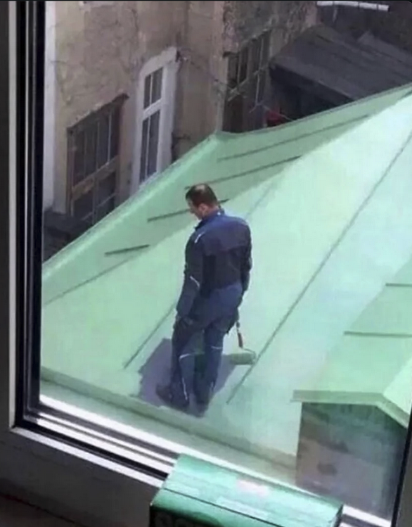 Painter on roof surrounded by fresh green paint and him standing in the middle looking down realizing that he can't go anywhere without stepping in the wet pain.