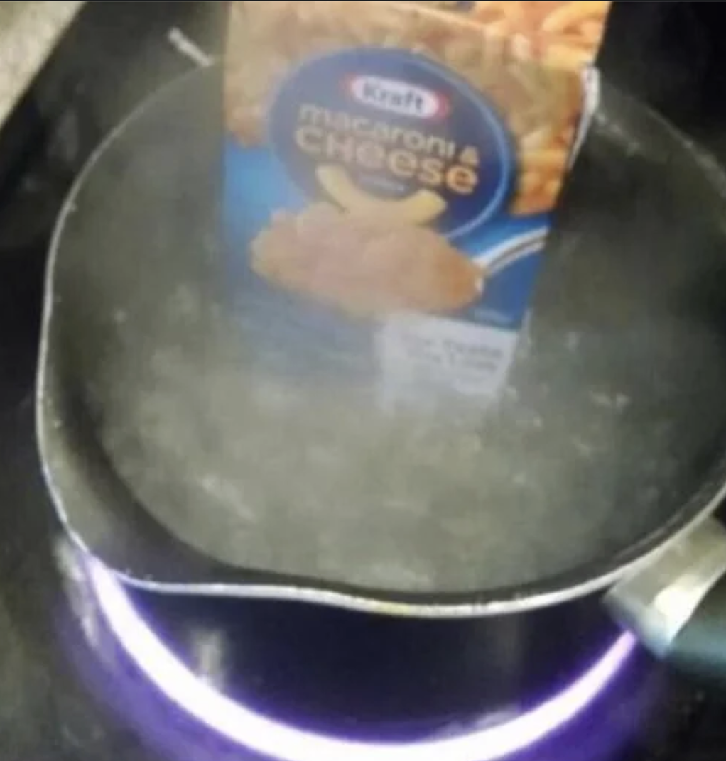 A box of Kraft Mac and Cheese in a boiling pot of water. The box is unopened.