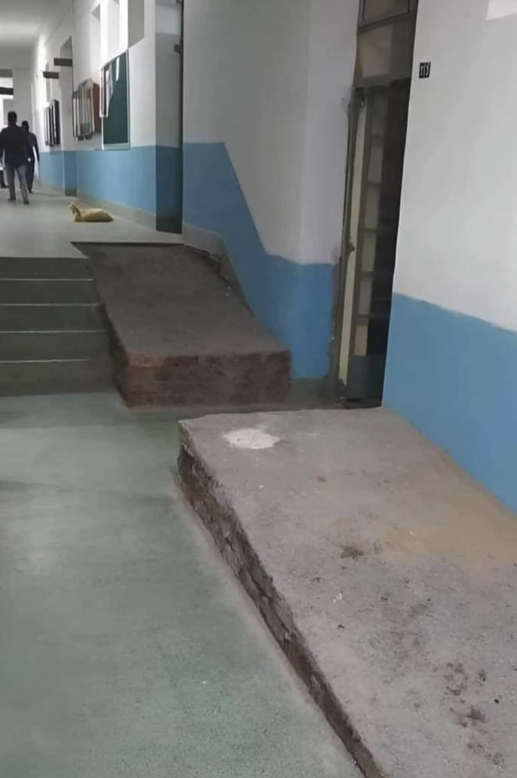 A ramp in a hallway that has a gap in the middle because on the wall next to it is an open door, otherwise the ramp would be blocking the door.