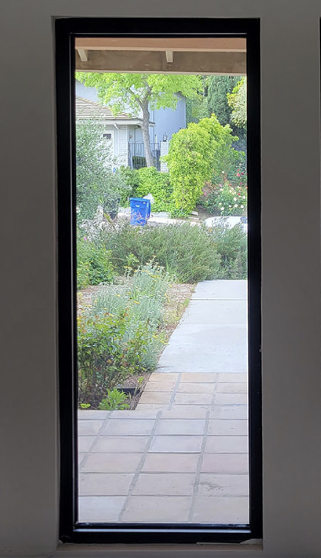 A physical vertical window looking outside to a walkway, nature, and the real world.