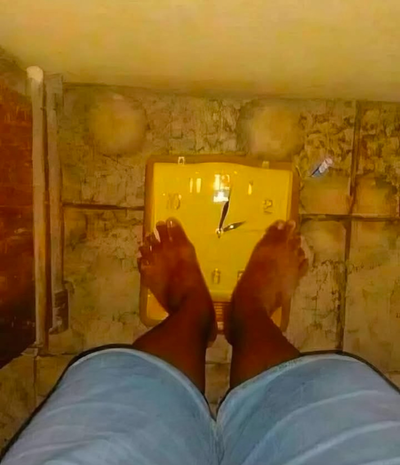 POV someone standing on what appears to be a scale to measure their weight but instead it looks like they are standing on a wall clock showing about 2 PM.